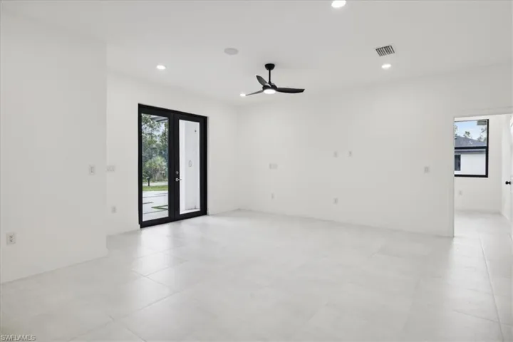 Empty room featuring plenty of natural light, ceiling fan, and french doors