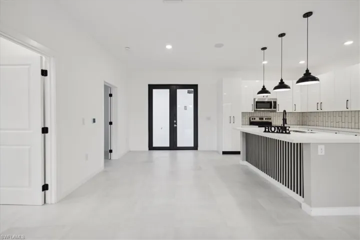 Kitchen with white cabinetry, decorative light fixtures, stainless steel appliances, decorative backsplash, and french doors