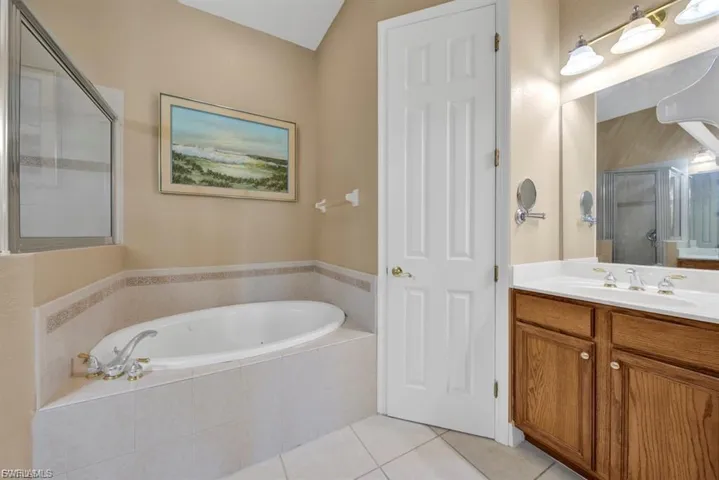 Full bathroom with vanity, tile patterned flooring, a garden tub, and a shower stall