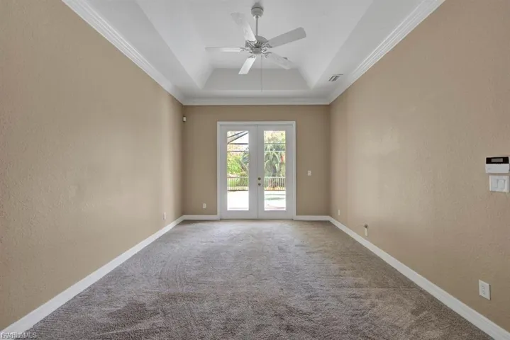 Spare room featuring a textured wall, crown molding, carpet flooring, french doors, and ceiling fan