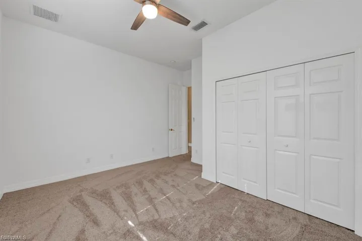 Unfurnished bedroom featuring carpet floors, a closet, and a ceiling fan