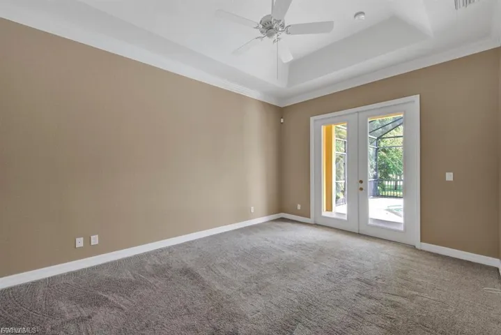 Spare room with french doors, carpet flooring, a ceiling fan, a raised ceiling, and ornamental molding