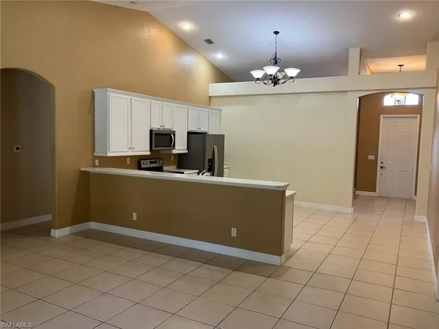 Kitchen with appliances with stainless steel finishes, white cabinets, a peninsula, light countertops, and recessed lighting