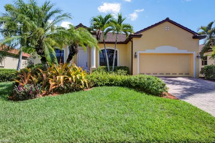 Mediterranean / spanish-style house featuring stucco siding, driveway, a front lawn, a garage, and a tile roof