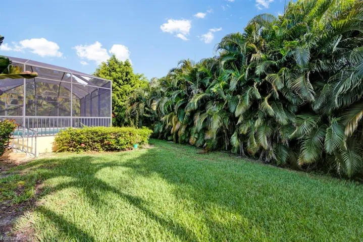 View of green lawn with an outdoor pool and glass enclosure