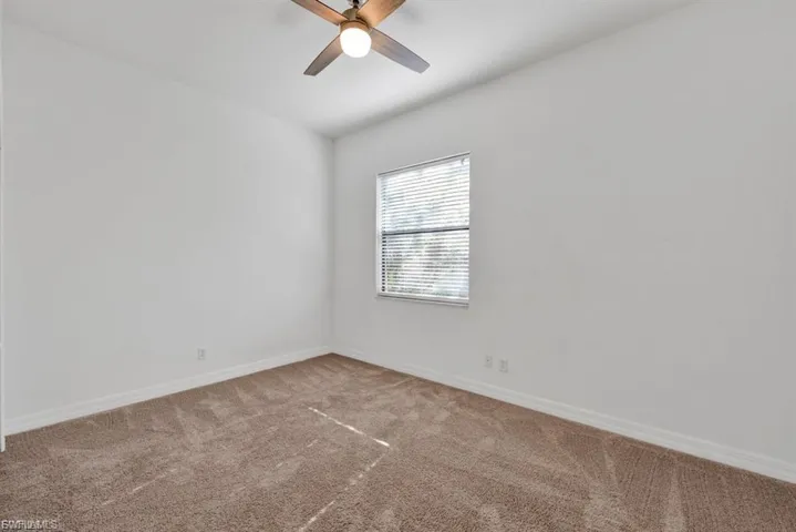 Empty room featuring carpet and a ceiling fan