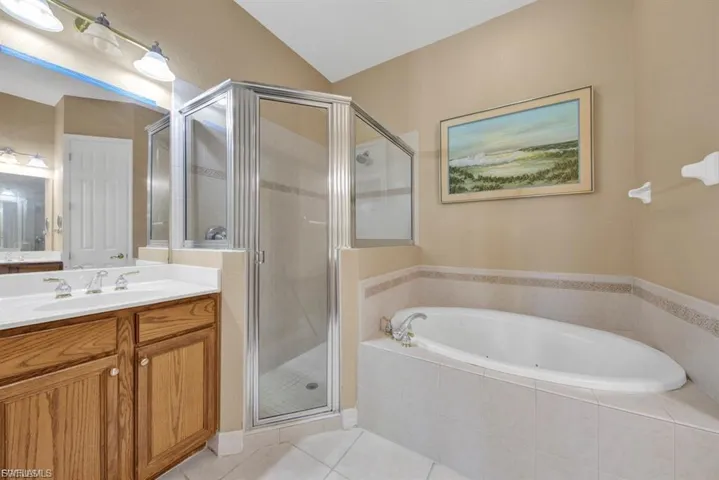 Bathroom with vanity, a jetted tub, a shower stall, and tile patterned floors