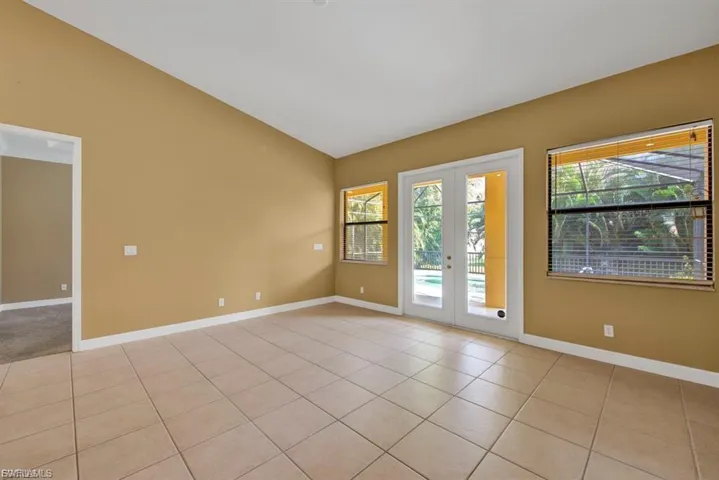 Unfurnished room featuring vaulted ceiling, light tile patterned floors, and french doors