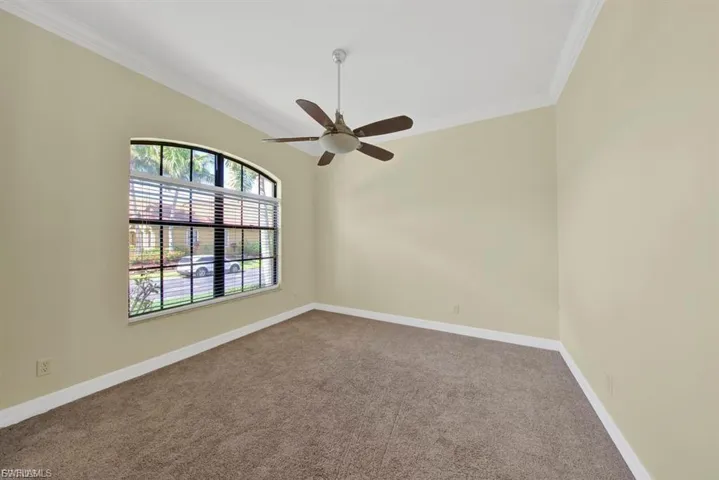Carpeted spare room with crown molding and ceiling fan