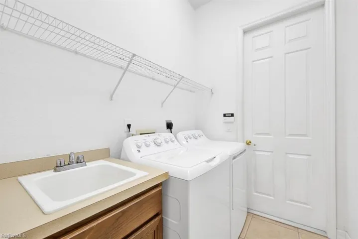 Laundry room with washing machine and dryer and light tile patterned floors