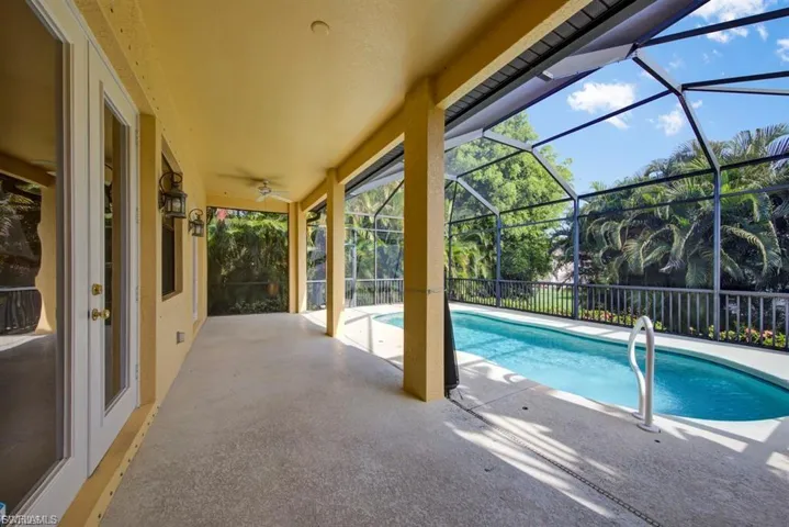 Swimming pool with a patio area, glass enclosure, and a ceiling fan