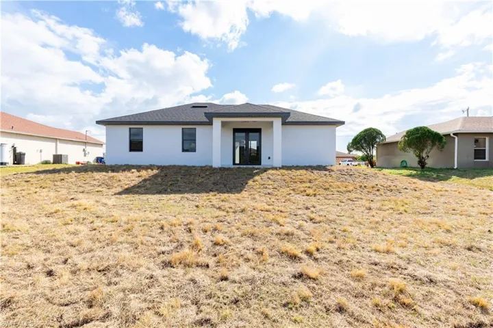 Rear view of property with cooling unit and a yard