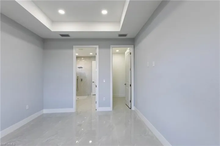 Unfurnished bedroom featuring connected bathroom, a spacious closet, and a raised ceiling
