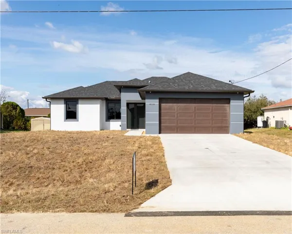 View of front of property featuring a garage, central AC unit, and a front lawn