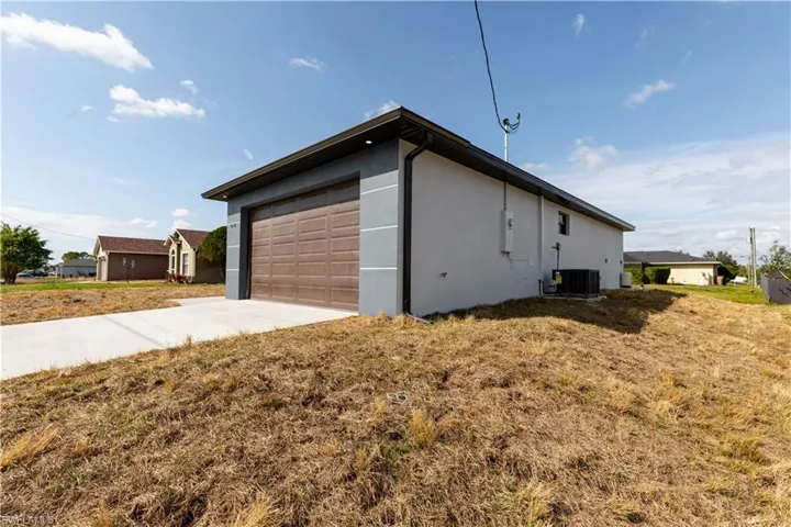 View of side of home featuring a garage, central air condition unit, and a lawn