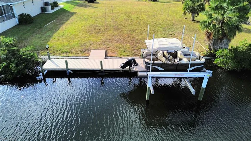 Dock area featuring a water view, boat lift, and a lawn