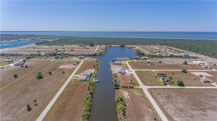 Aerial view of property's location featuring a large body of water and a forest