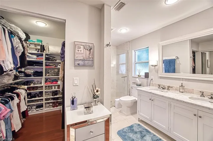 Bathroom with tiled shower, vanity, and toilet