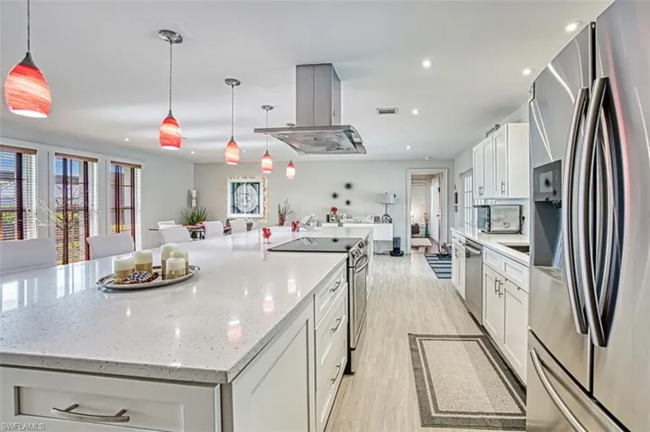 Kitchen featuring appliances with stainless steel finishes, hanging light fixtures, a spacious island, white cabinets, and island exhaust hood