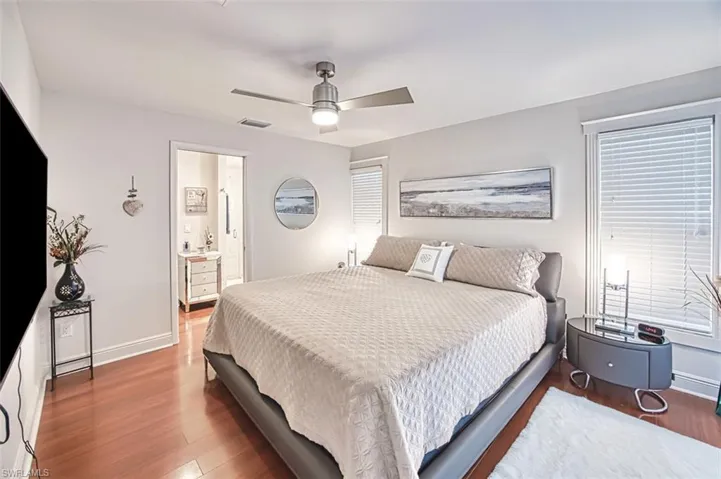 Bedroom featuring hardwood / wood-style flooring, ceiling fan, and ensuite bathroom