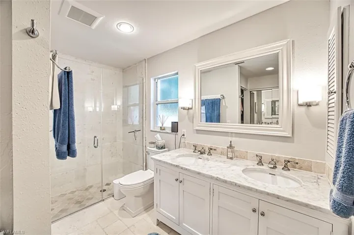Bathroom featuring an enclosed shower, vanity, and toilet
