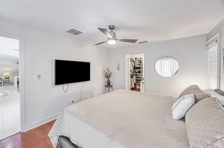 Bedroom with hardwood / wood-style flooring, a walk in closet, a closet, and ceiling fan
