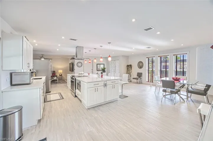 Kitchen with white cabinetry, stainless steel appliances, a center island, a kitchen bar, and decorative light fixtures