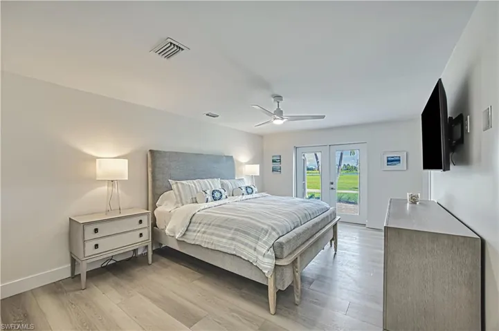 Bedroom featuring light wood finished floors, french doors, access to exterior, and ceiling fan