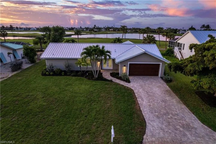 Ranch-style house with a metal roof, a lawn, decorative driveway, and an attached garage