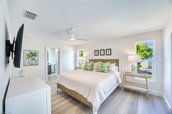 Bedroom featuring light wood-type flooring, ensuite bath, and a ceiling fan