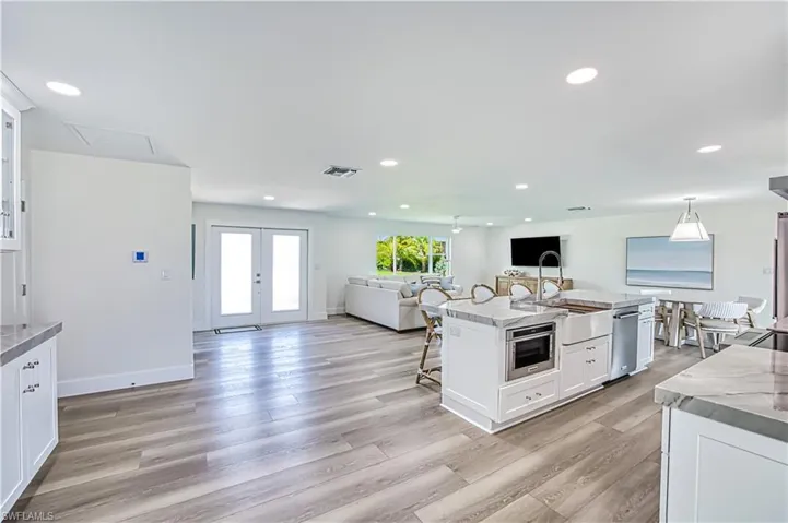 Kitchen with white cabinets, a kitchen bar, open floor plan, recessed lighting, and french doors
