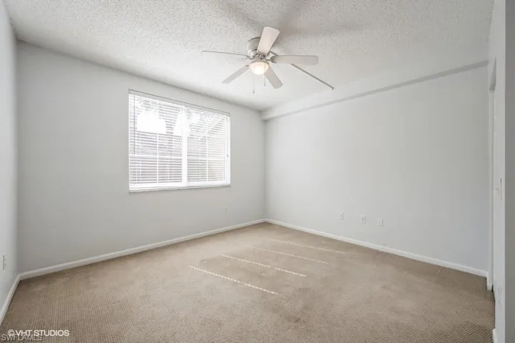 Carpeted empty room featuring ceiling fan and a textured ceiling