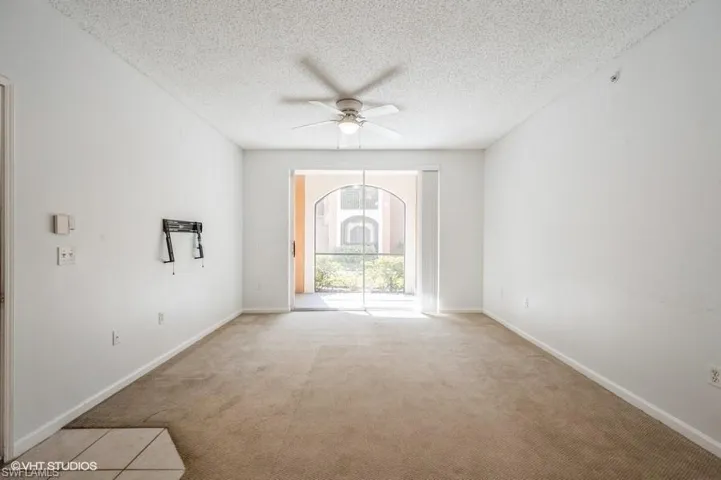 Unfurnished room featuring ceiling fan, light colored carpet, and a textured ceiling