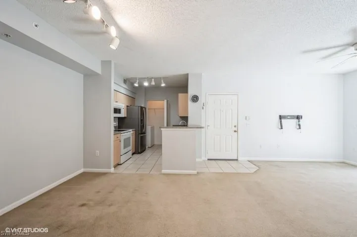 Unfurnished living room featuring light carpet, a textured ceiling, track lighting, and ceiling fan