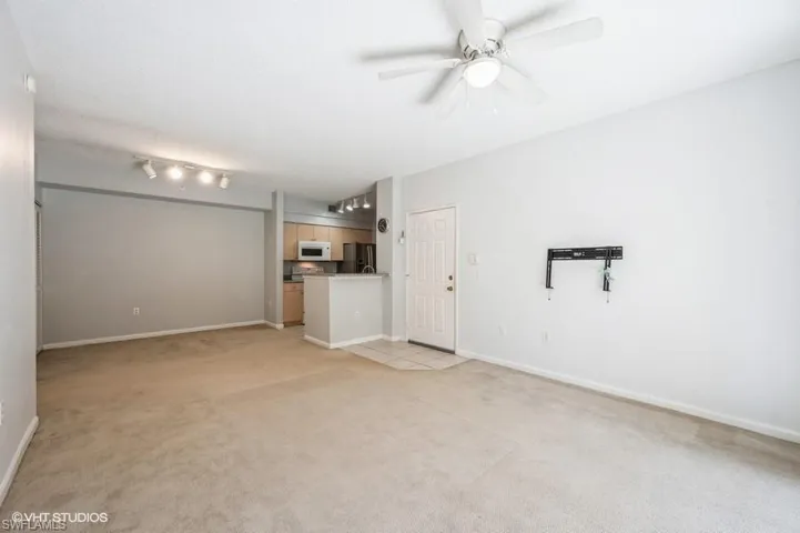 Unfurnished living room with ceiling fan and light colored carpet