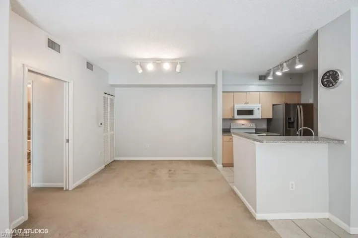 Kitchen featuring light carpet, electric range oven, a textured ceiling, stainless steel fridge, and kitchen peninsula