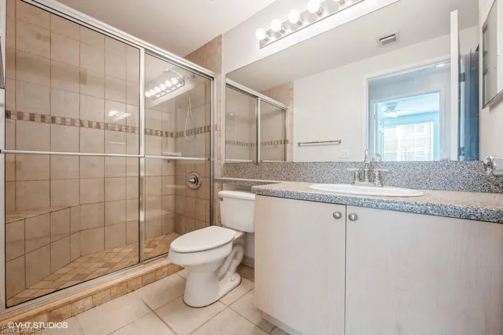 Bathroom with tile patterned flooring, vanity, toilet, and walk in shower