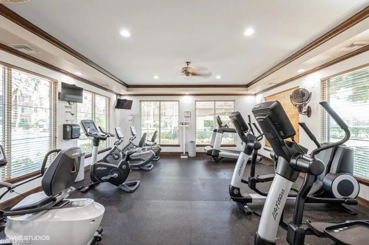 Gym with crown molding and ceiling fan