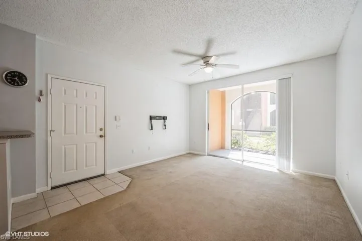 Carpeted spare room with a textured ceiling and ceiling fan