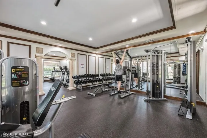 Exercise room featuring crown molding and decorative columns