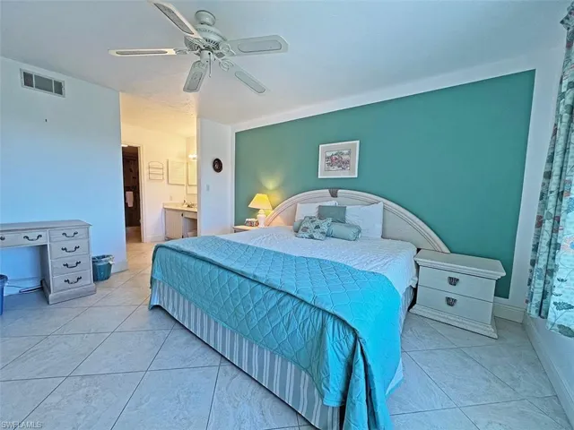Bedroom featuring a ceiling fan, ensuite bath, and light tile patterned floors