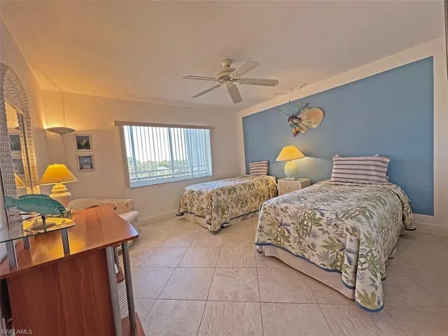 Tiled bedroom featuring a ceiling fan and baseboards