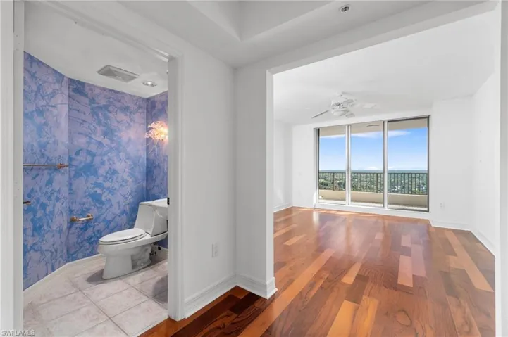 Bathroom featuring expansive windows, hardwood / wood-style flooring, toilet, and ceiling fan