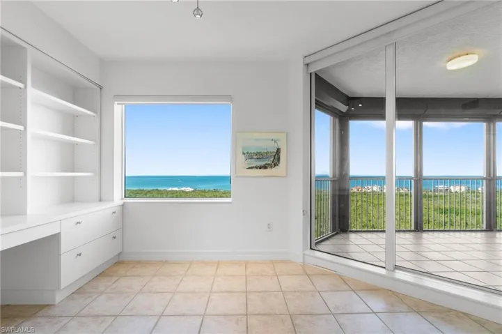Spare room featuring a water view, built in desk, a textured ceiling, and light tile patterned floors