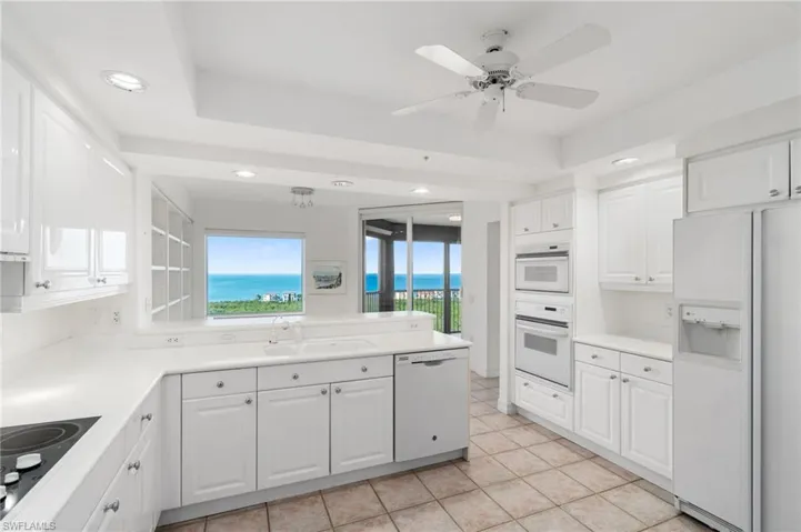 Kitchen featuring white cabinets, ceiling fan, sink, and white appliances