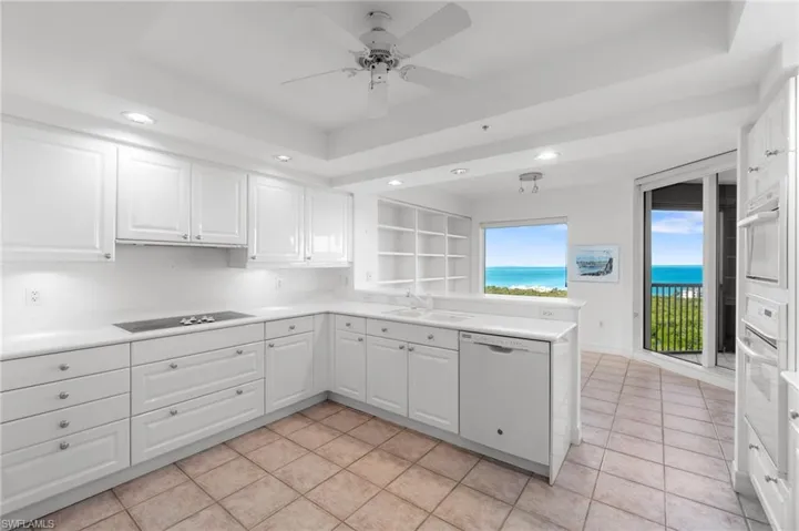 Kitchen featuring a raised ceiling, white cabinets, a water view, and white appliances