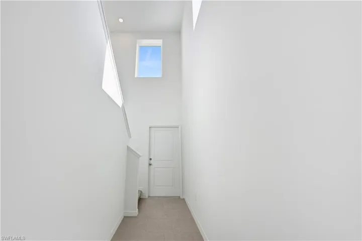Two-story entryway featuring high ceilings, white painted walls, a rectangular window, and recessed lighting