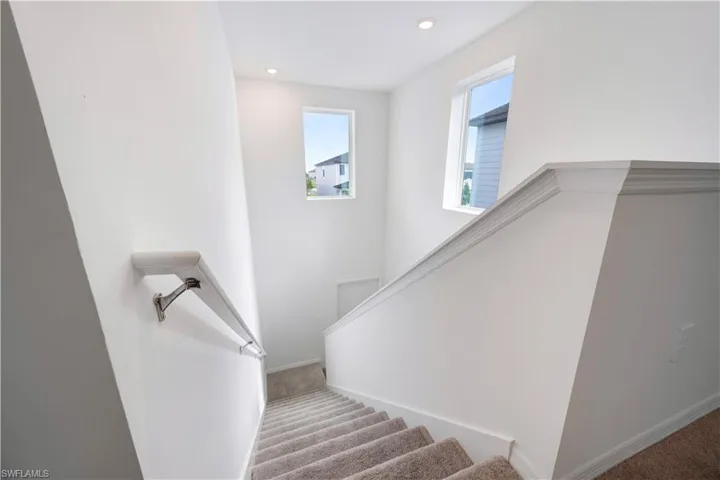 Carpeted staircase with white balustrade and handrail