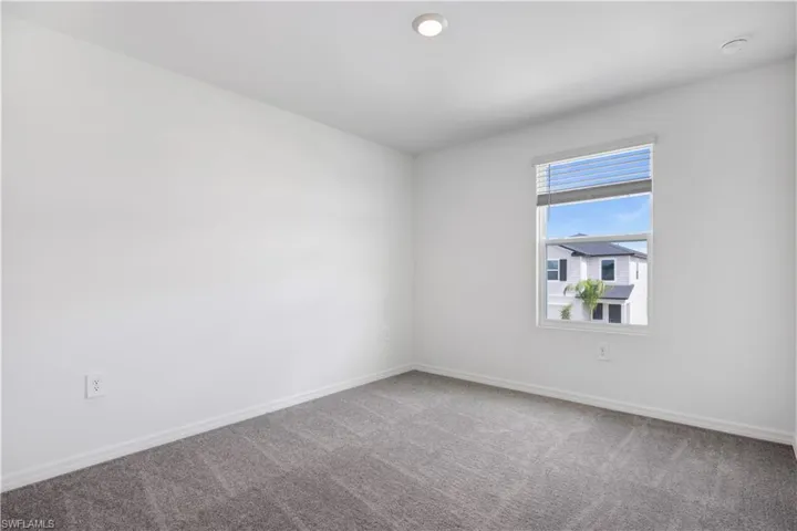 Bright room featuring neutral carpeting, white walls, and a single window with blinds