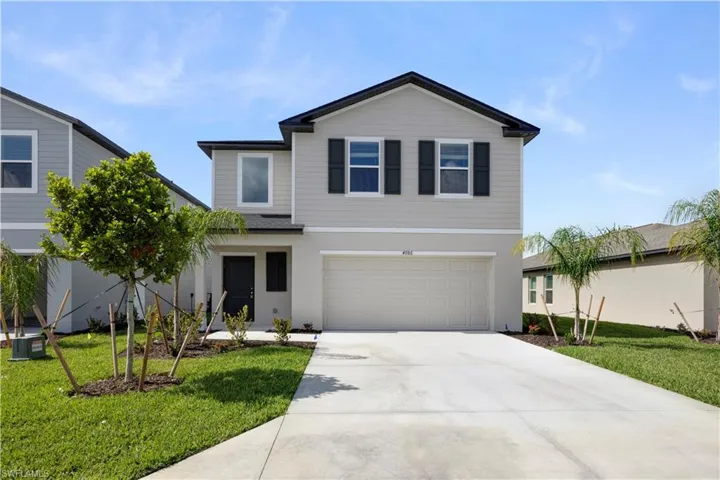Contemporary two-story residence featuring a light gray exterior, a two-car garage, and dark window shutters